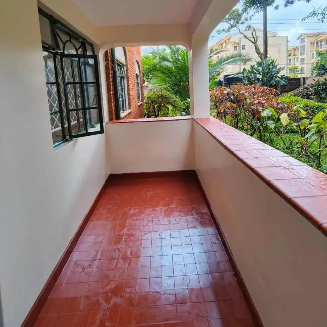 Covered balcony with terracotta tiles overlooking lush garden