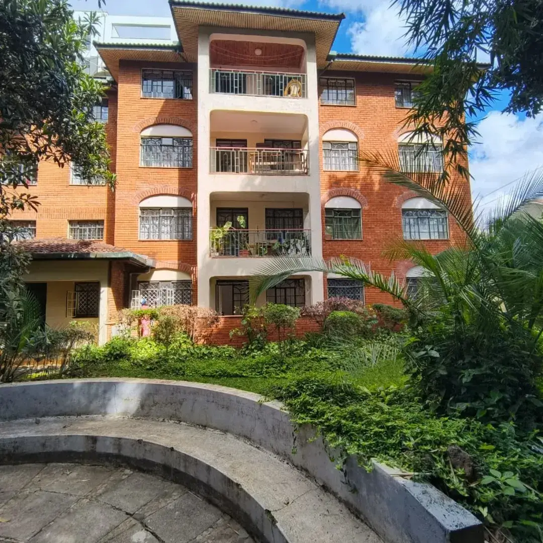 Multi-story brick residential building with balconies and landscaping