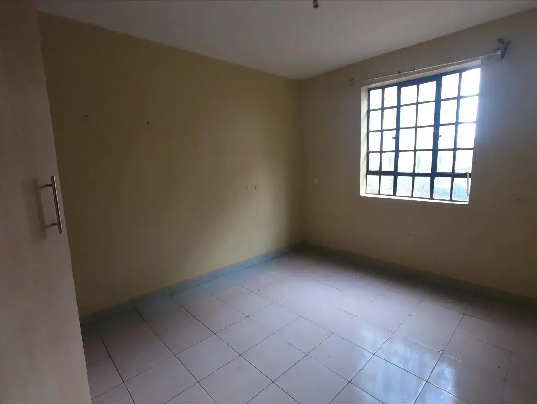 Empty bedroom with tiled floor and barred window