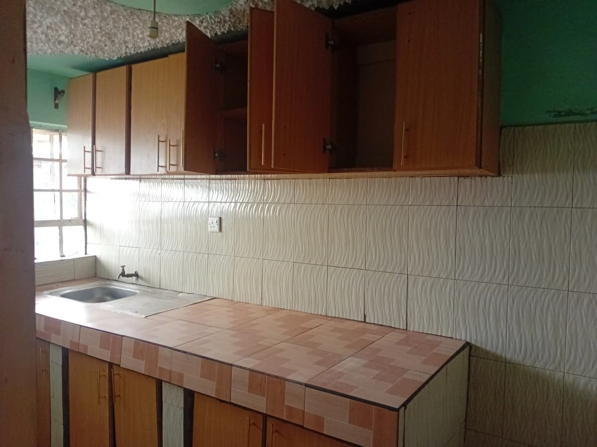 Compact kitchen with terracotta countertop and wooden cabinets
