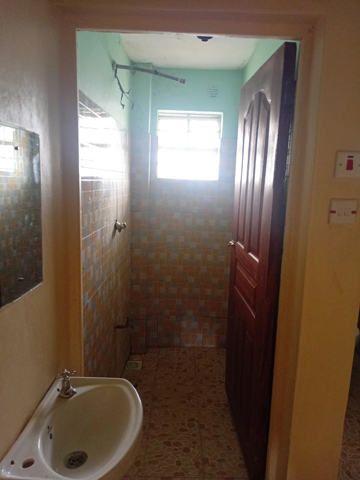 Narrow bathroom with sink, shower enclosure, natural light