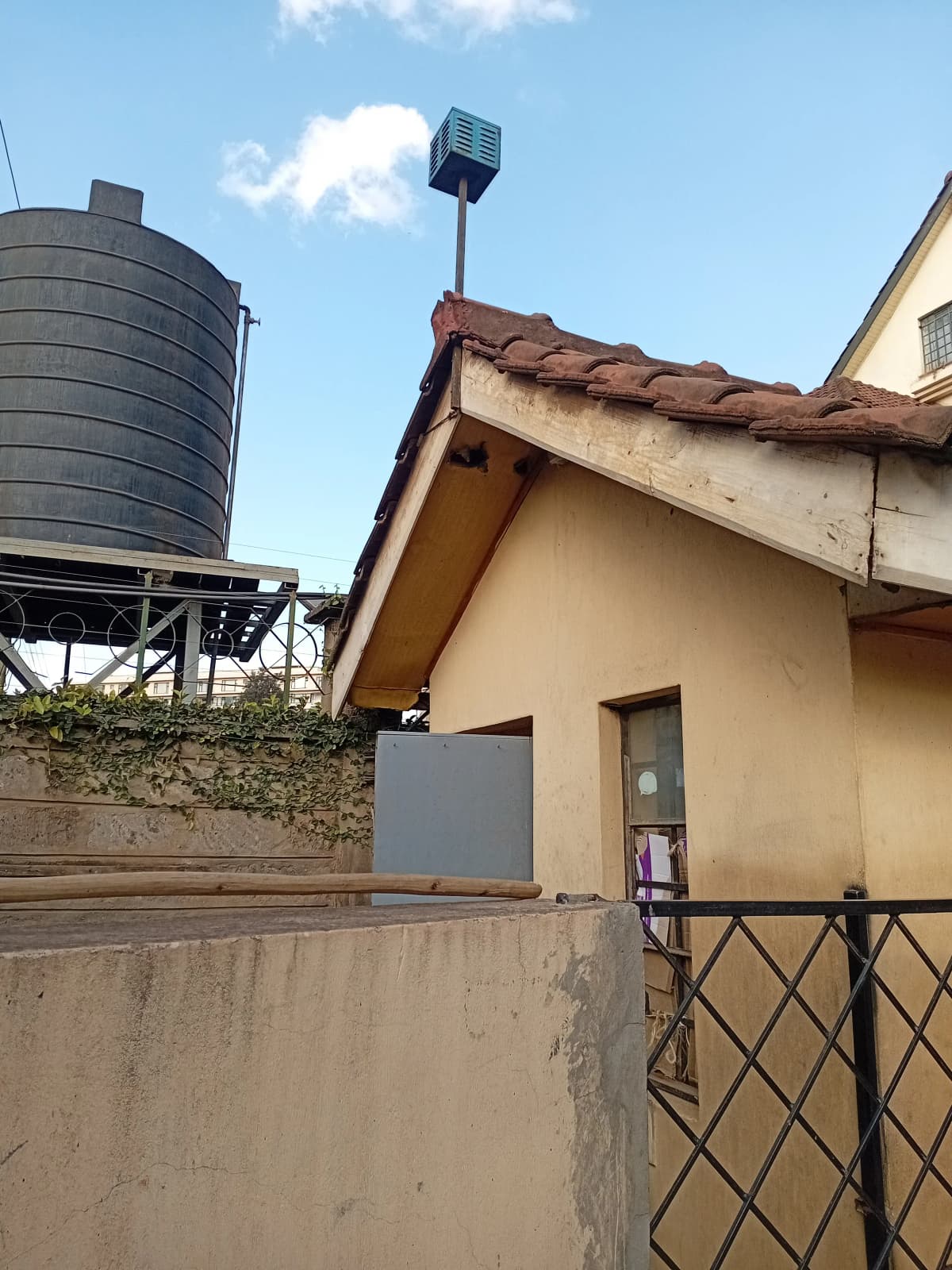 Residential compound with water tank and metal gate entrance