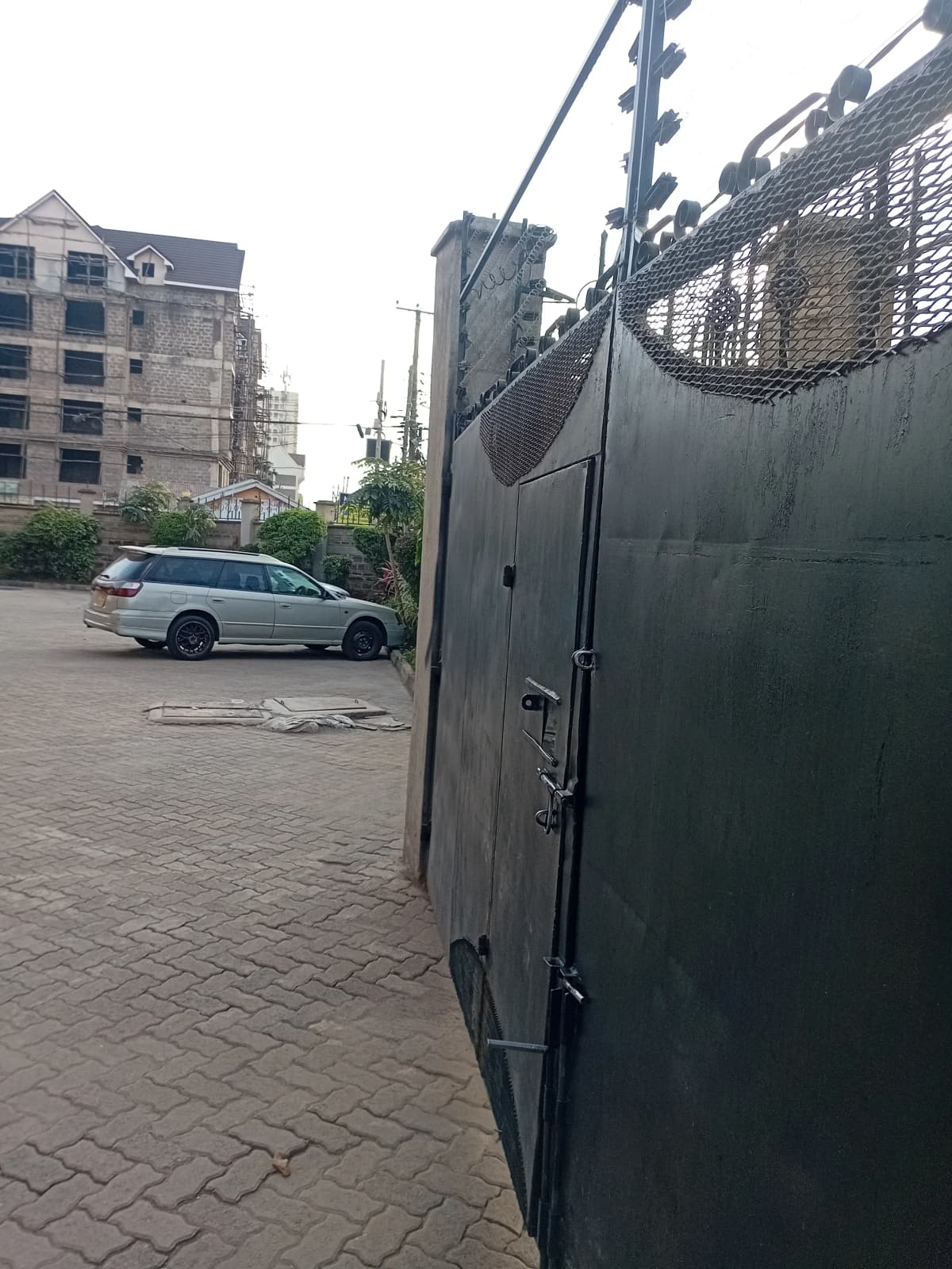Compound entrance with metal gate and paved driveway