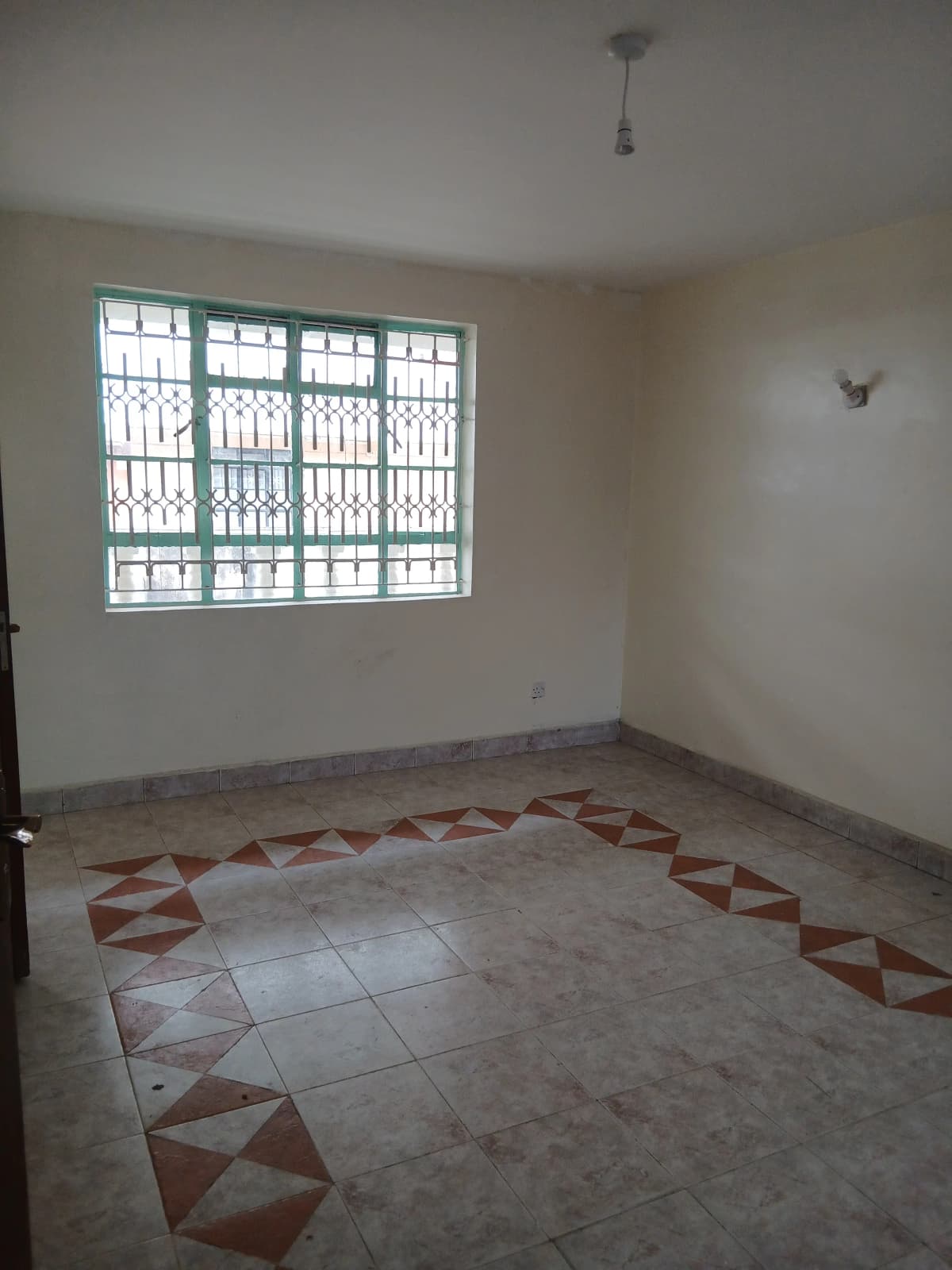 Spacious living room with geometric tile flooring and barred windows