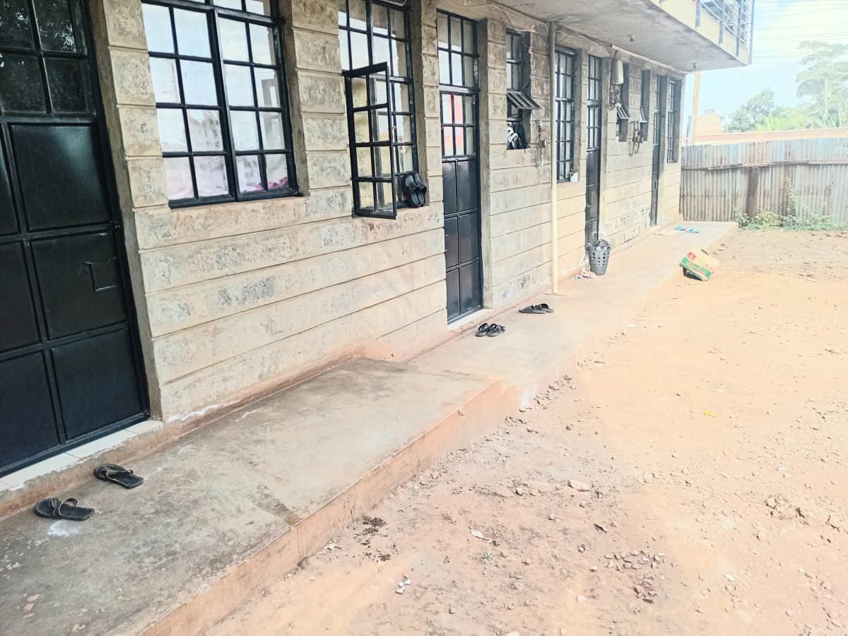 Building facade with multiple windows and dirt compound entrance