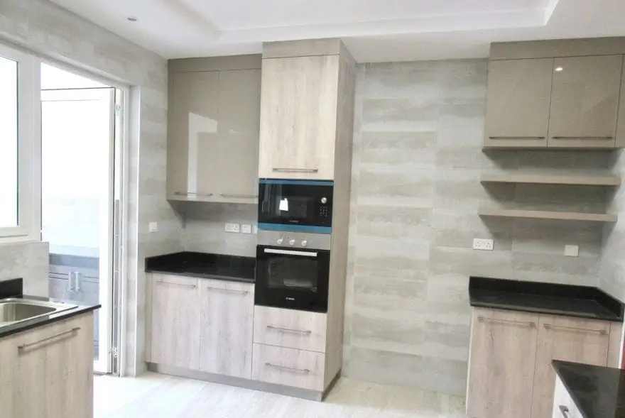 Modern kitchen with light wood cabinetry and black countertops