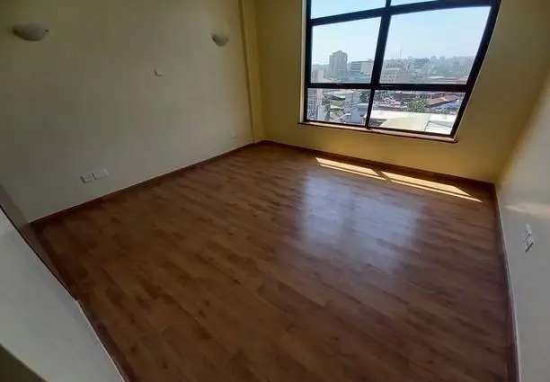 Spacious bedroom with wooden floors and city skyline views