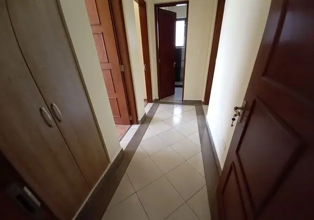 Tiled hallway corridor with multiple doors and natural light