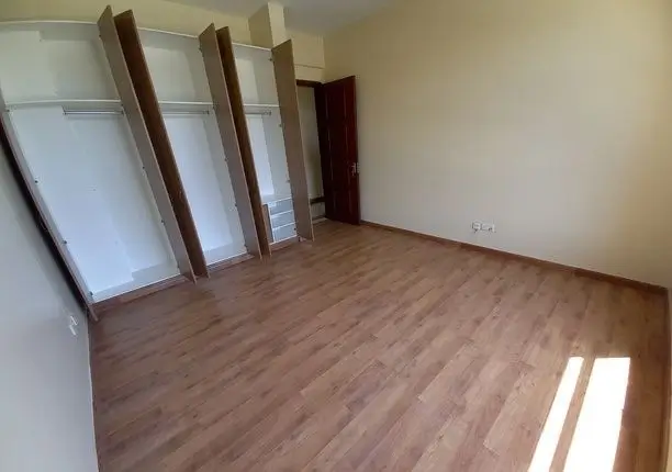 Spacious bedroom with wooden flooring and built-in wardrobes