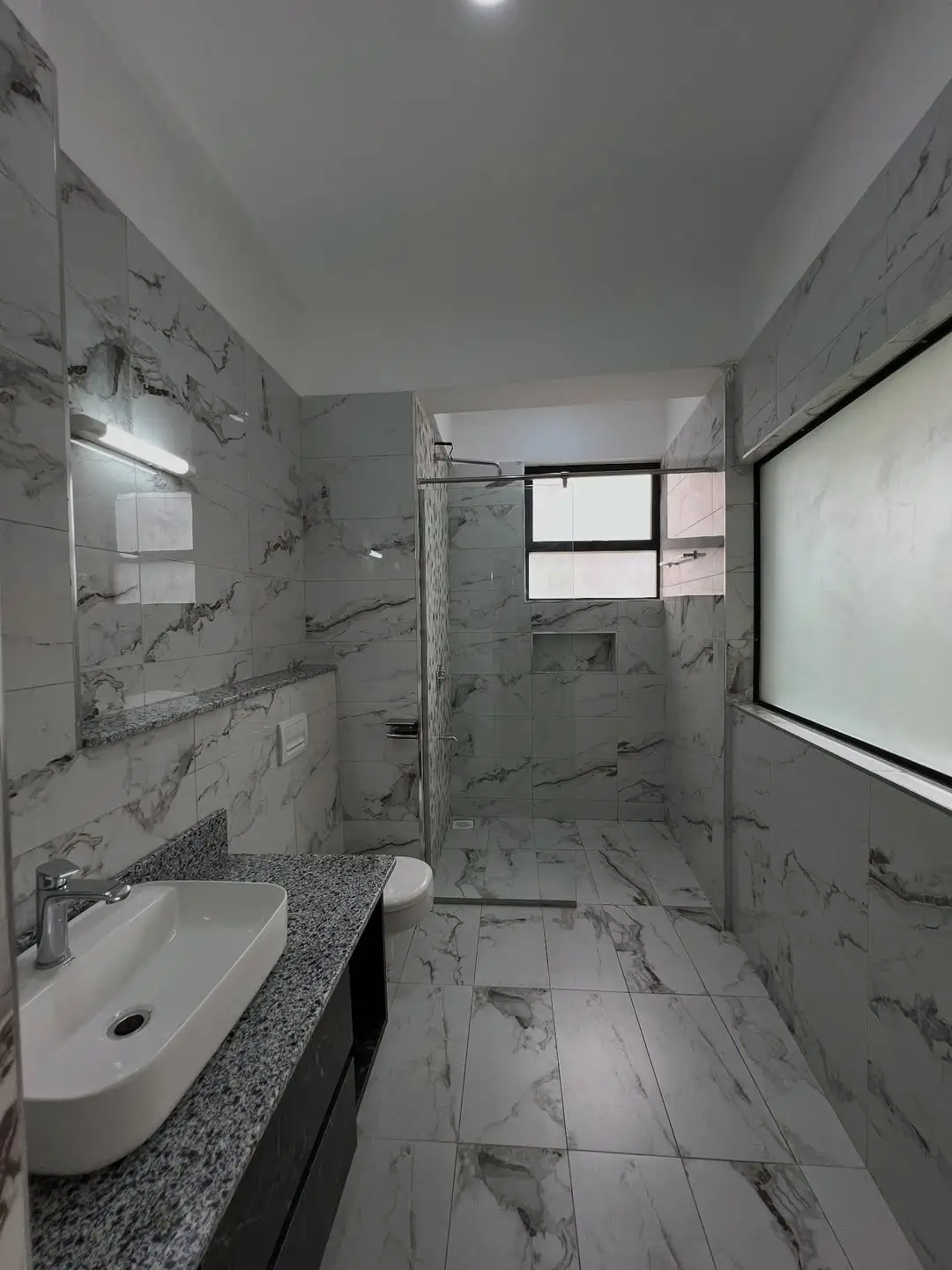 Modern bathroom with marble tiles, walk-in shower, granite countertop