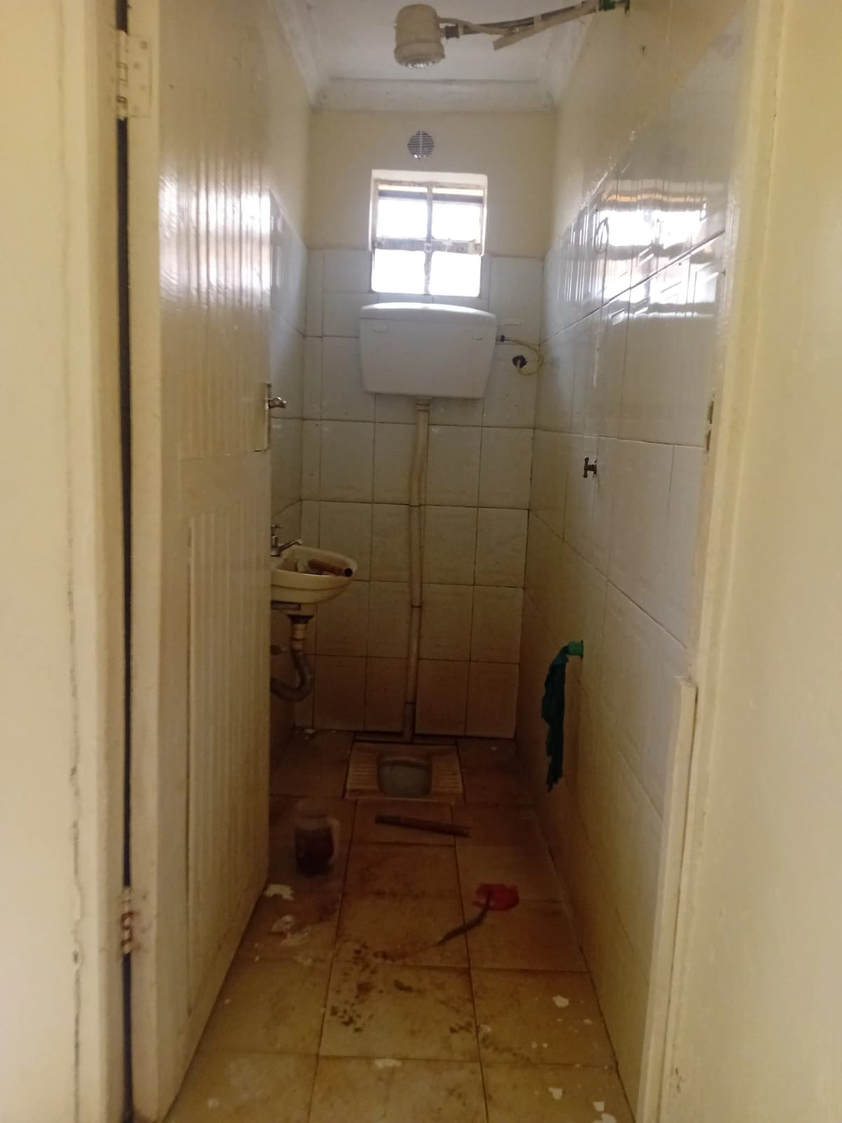 Narrow bathroom with toilet, shower enclosure, tiled walls