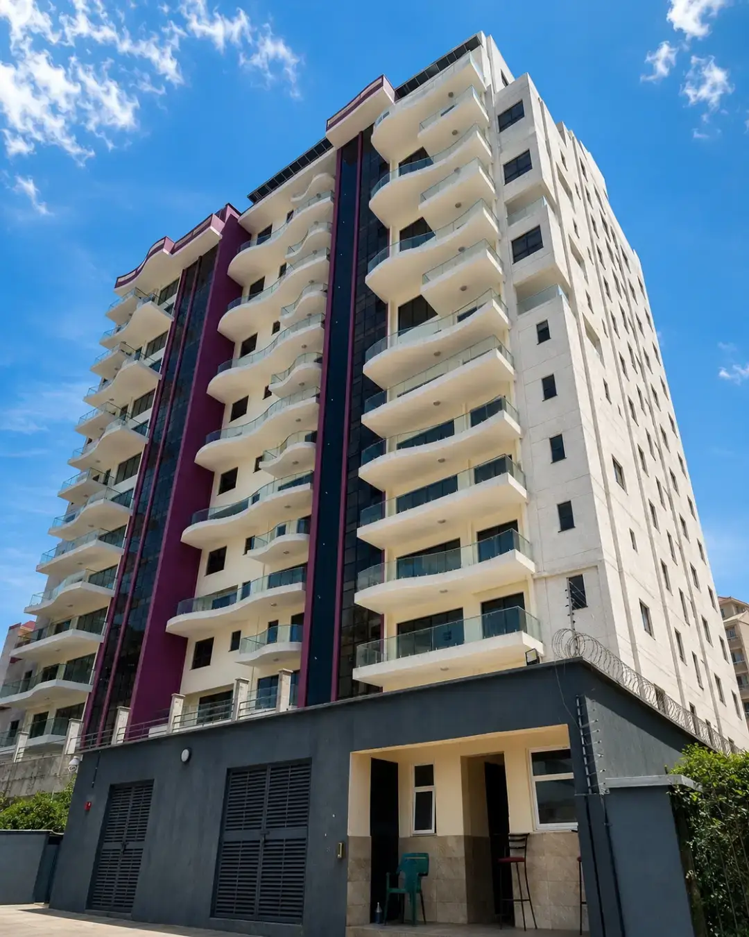 Tall white apartment block with purple accent and balconies