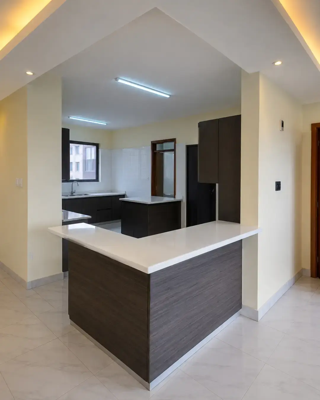 Modern dark-cabineted kitchen with white island breakfast bar