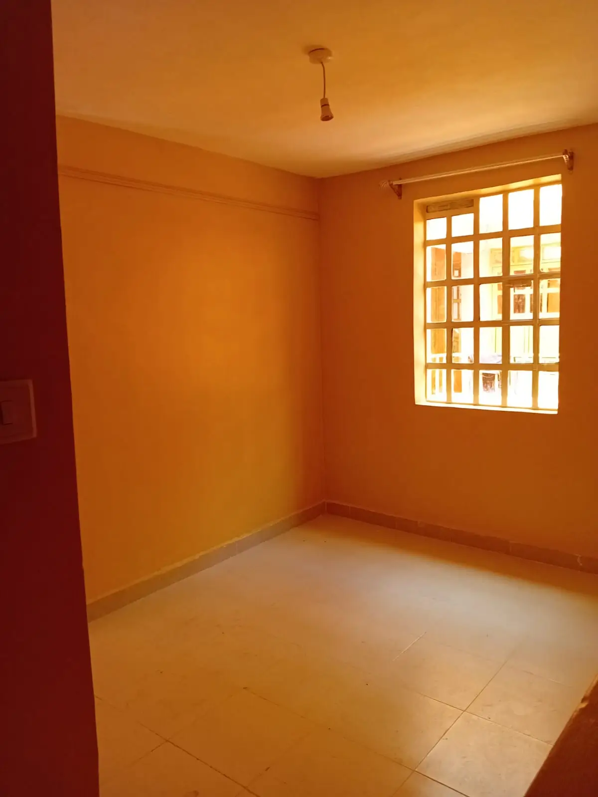 Empty bedroom with orange walls and barred window