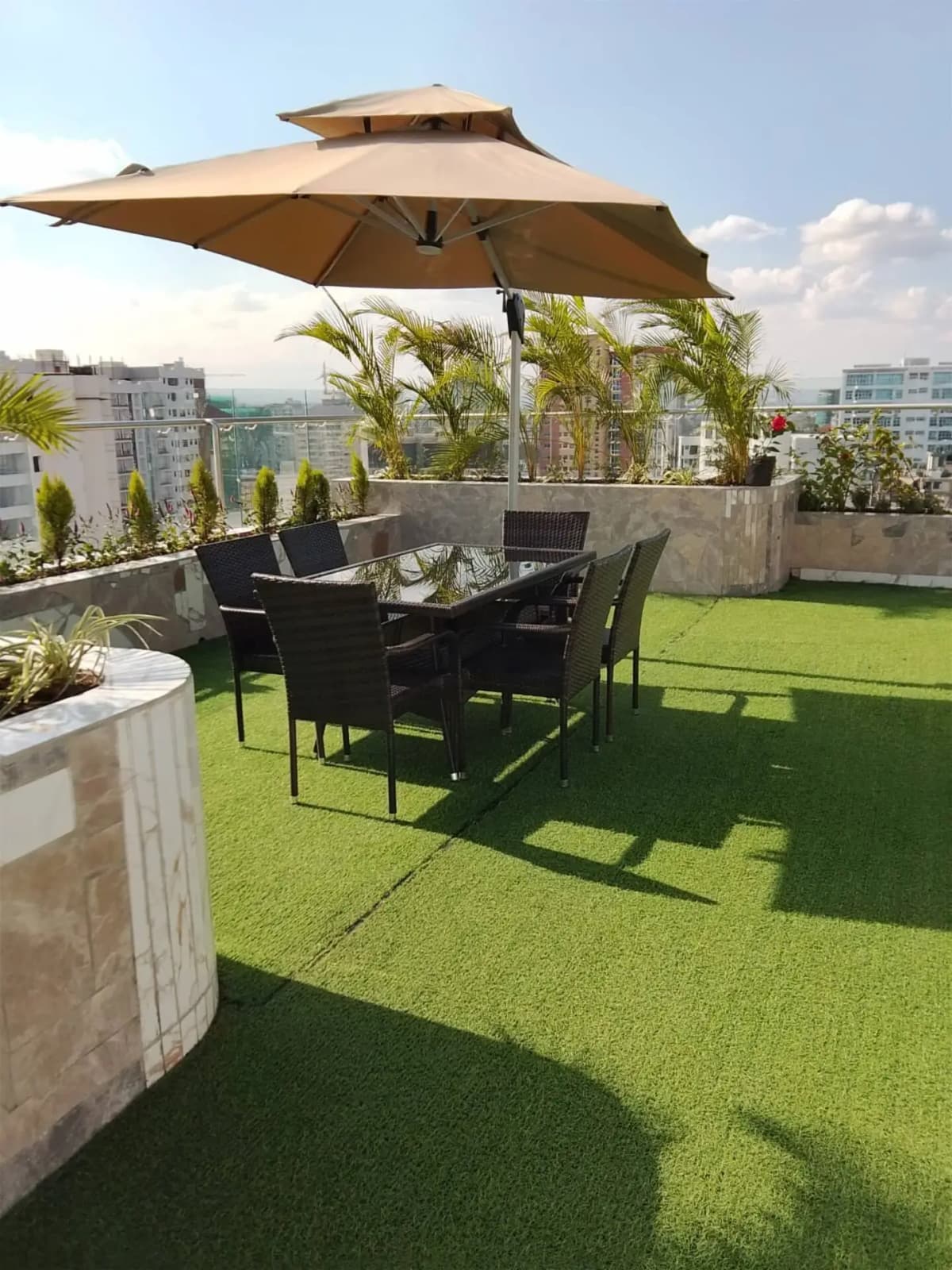 Rooftop terrace with artificial lawn, dining setup, city views