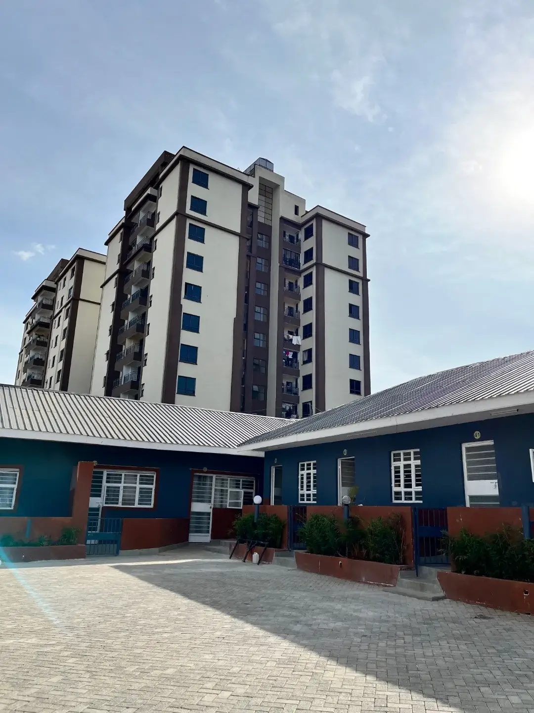 Modern multi-story residential tower with compound entrance