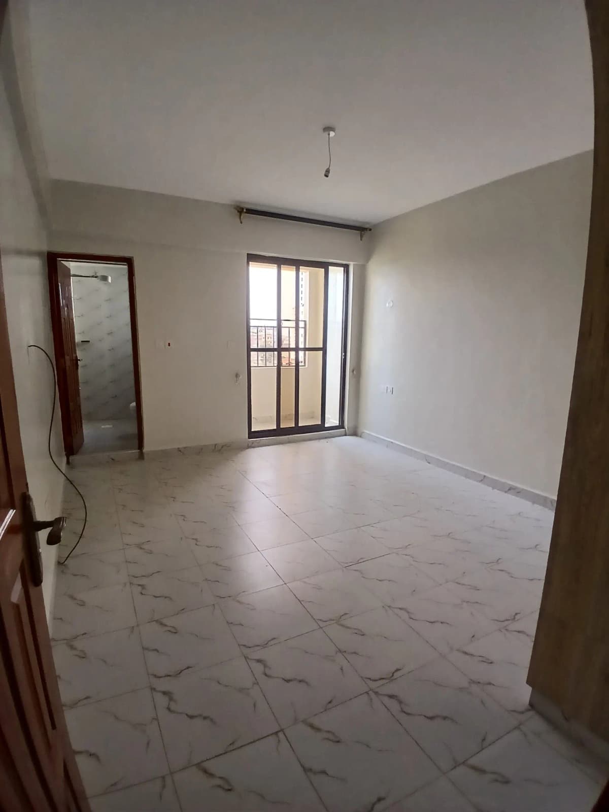 Spacious living room with marble flooring and balcony access