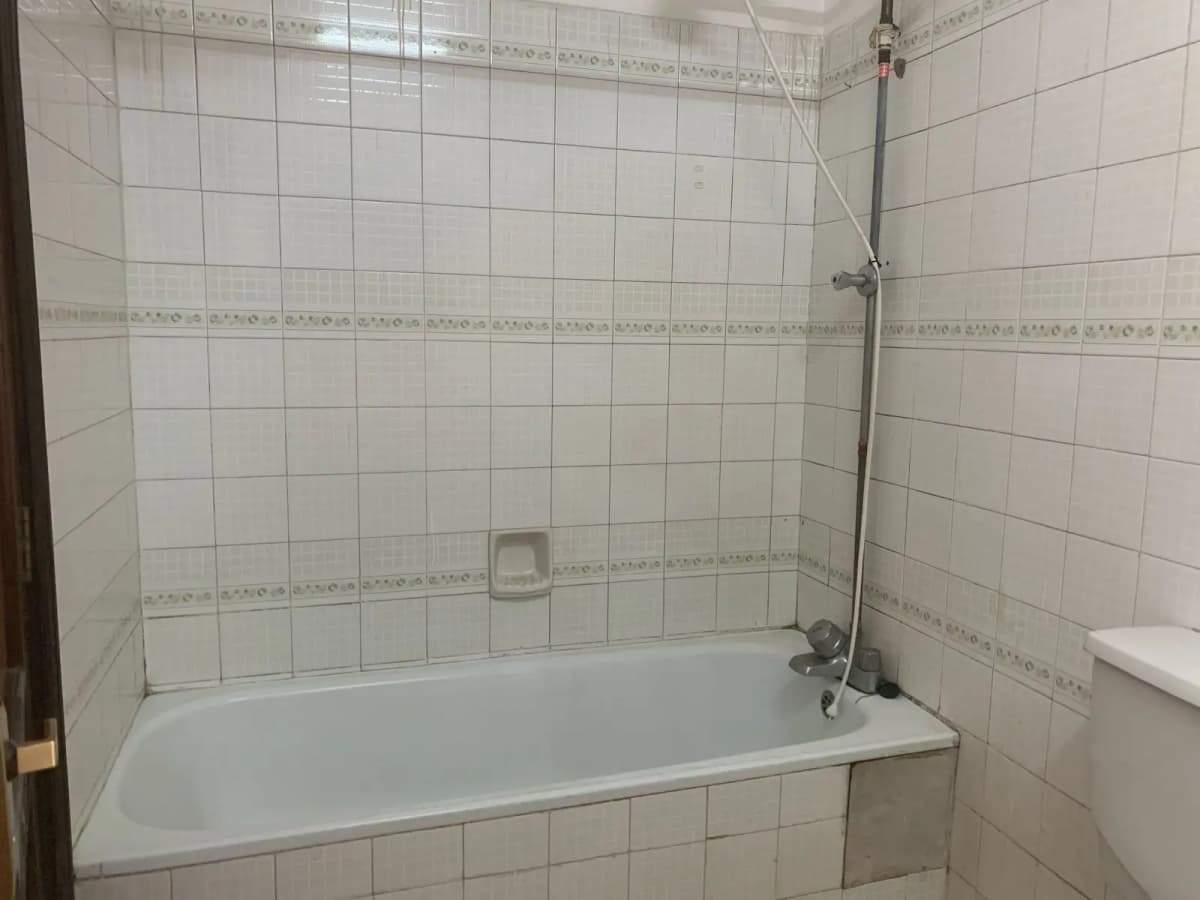 White tiled bathroom with bathtub and shower enclosure