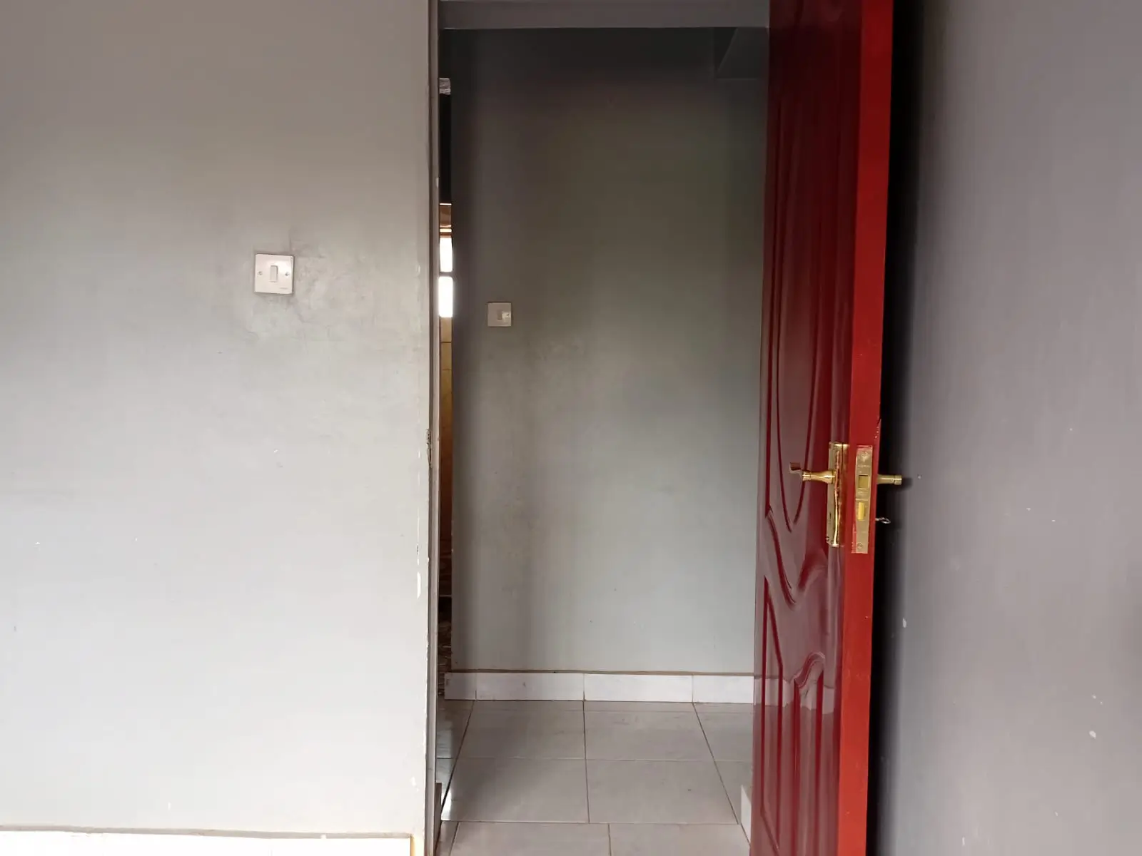 Building entrance corridor with red door and tiled flooring