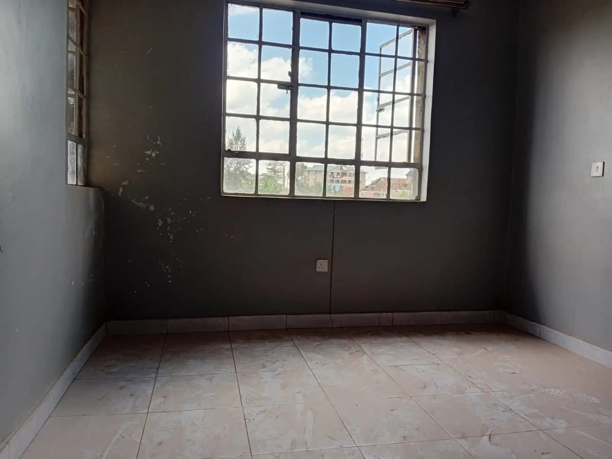 Empty bedroom with large window and tiled flooring