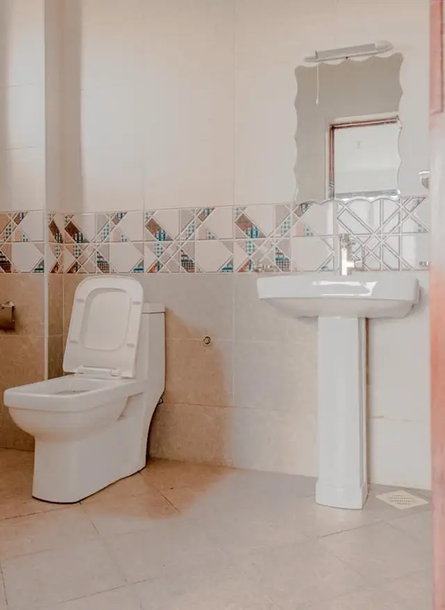 Clean bathroom with pedestal sink and modern toilet fixture
