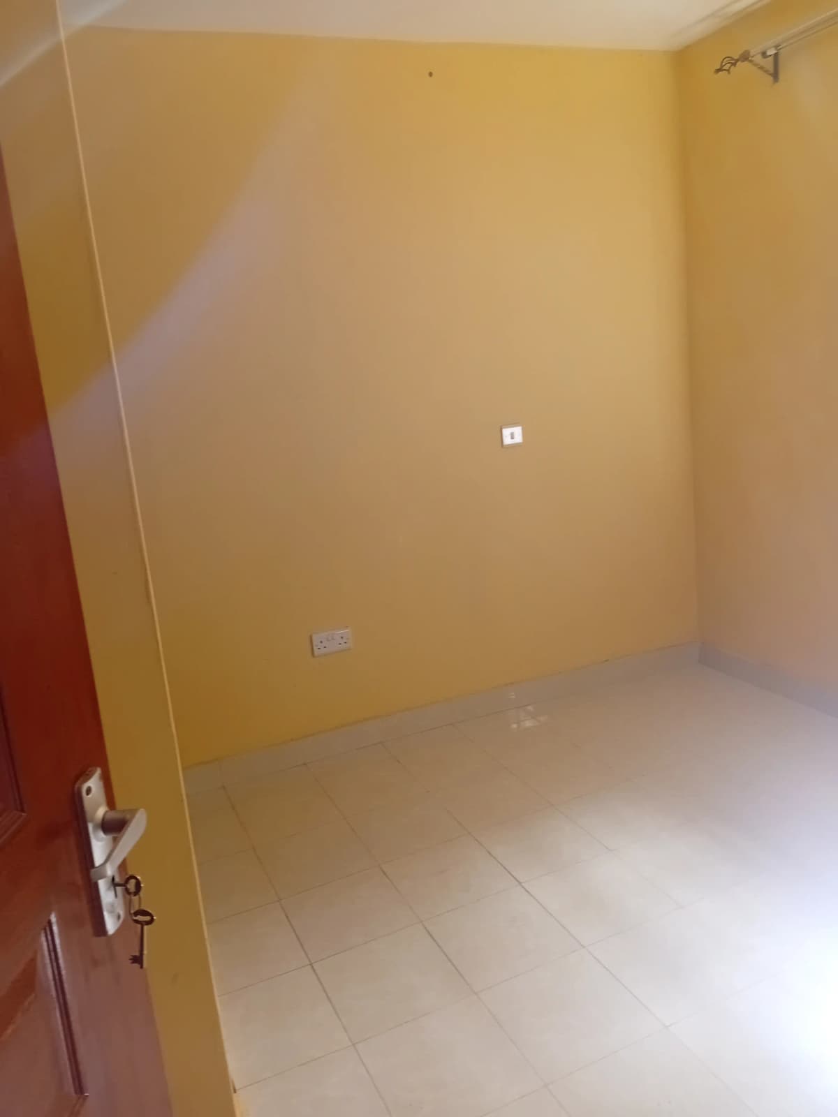 Empty bedroom with yellow walls and light tiling