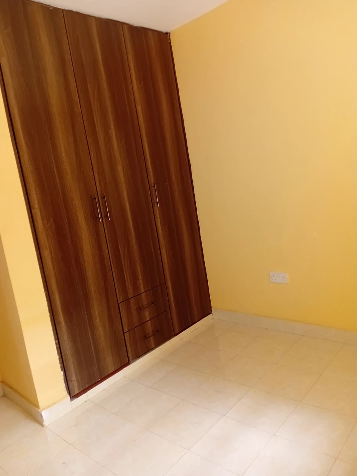 Empty bedroom with yellow walls and wooden wardrobe