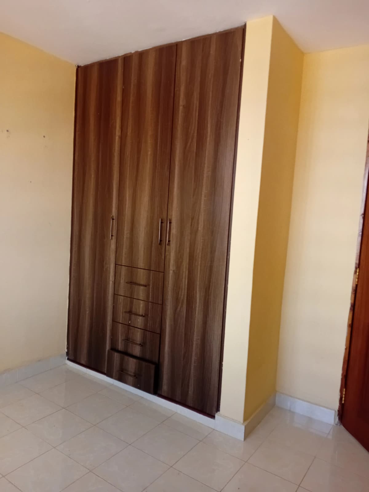 Bedroom with large wooden wardrobe and pale yellow walls
