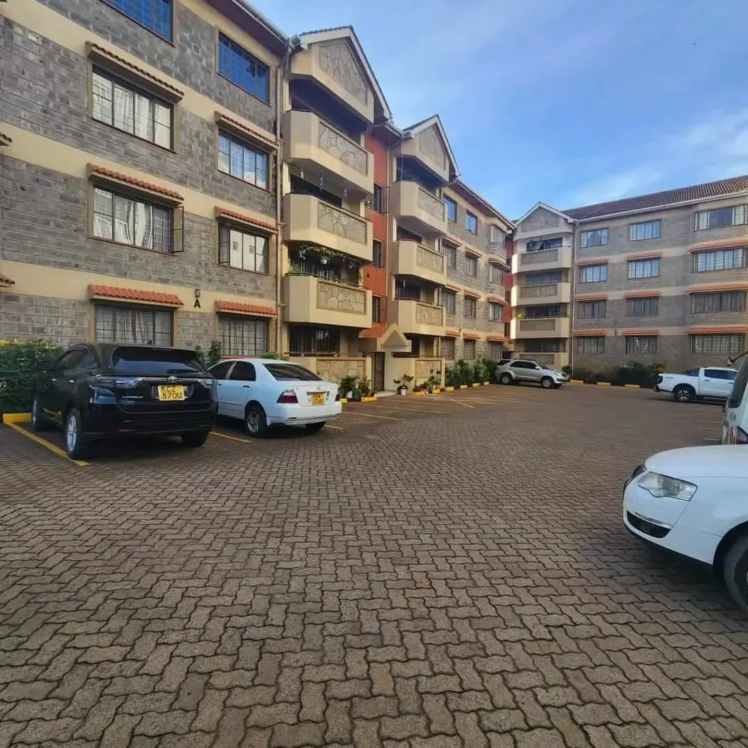Residential compound parking lot with multiple vehicles and buildings