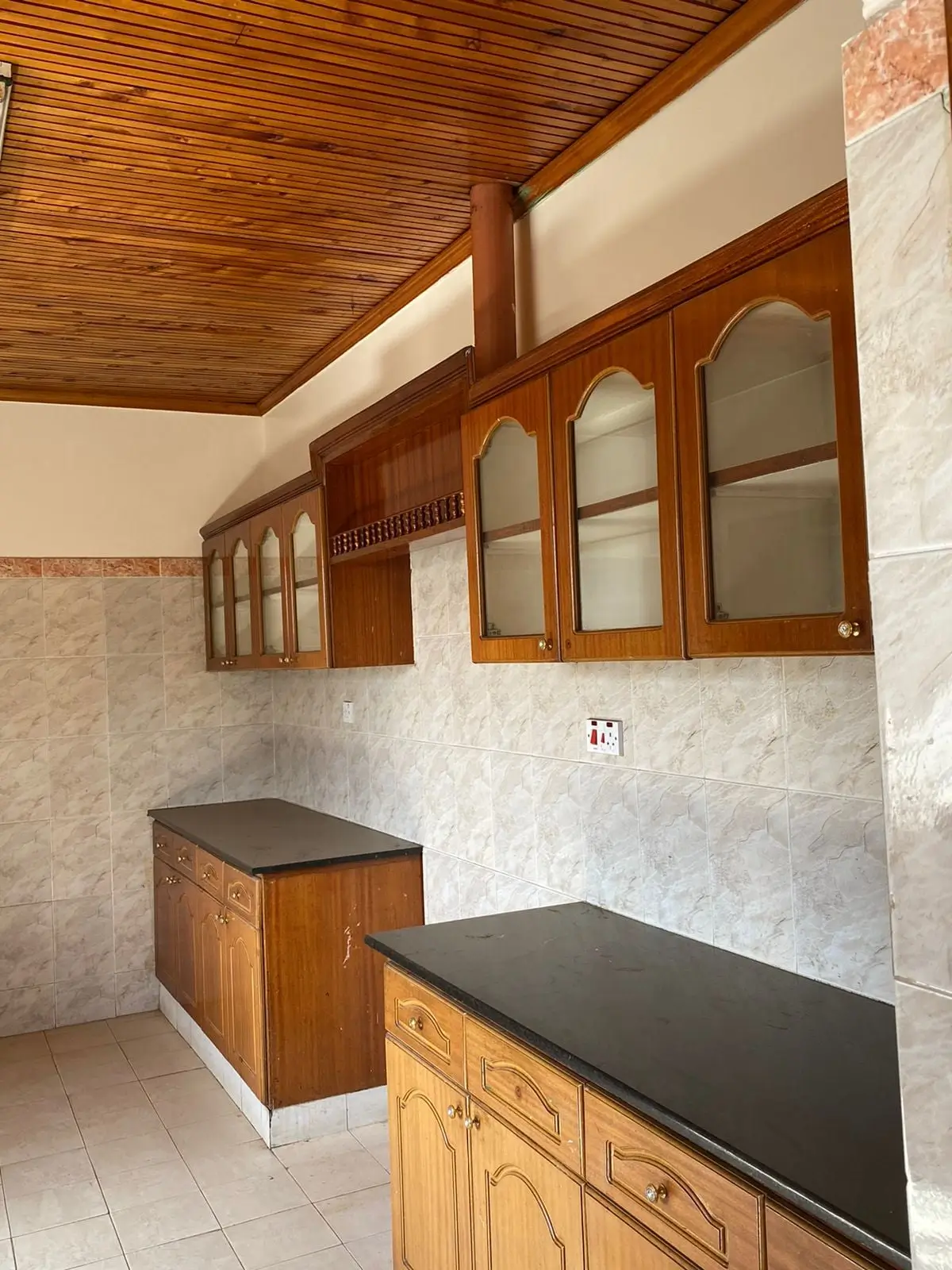 Kitchen with wooden cabinets, black countertops, and wall storage