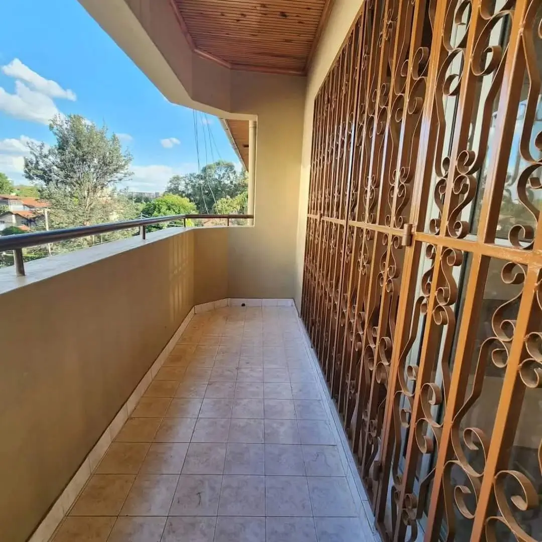Spacious balcony with decorative metal railing and garden views