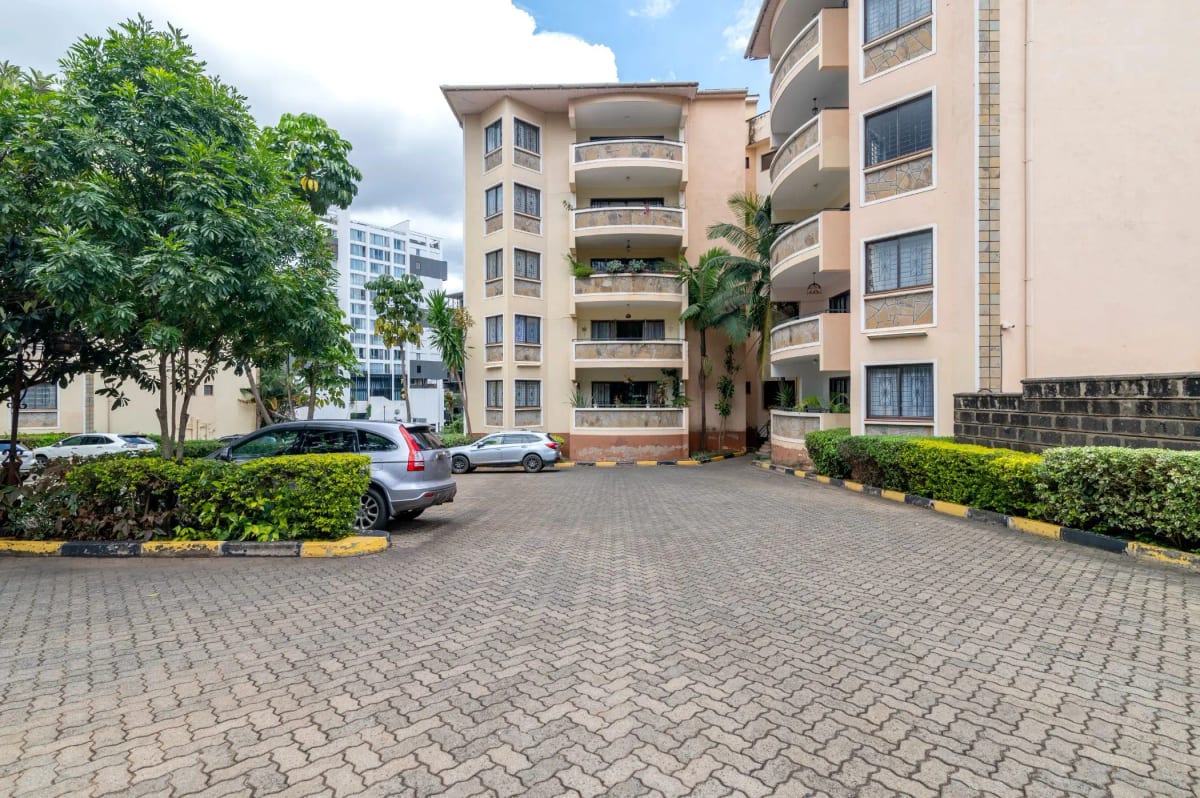Paved compound driveway with parked vehicles and apartment buildings