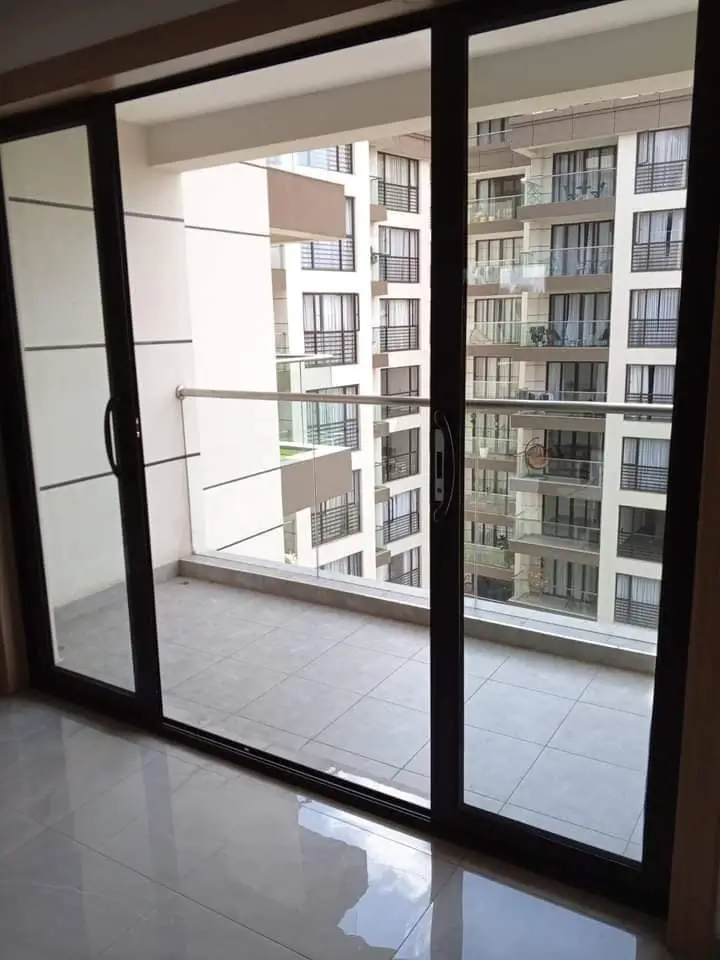 Modern balcony with black-framed glass doors overlooking apartment complex
