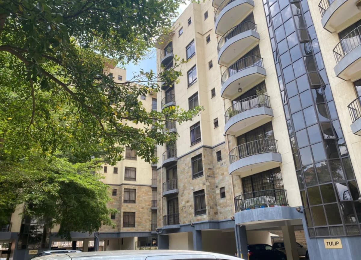 Multi-story residential building facade with balconies and tree foliage