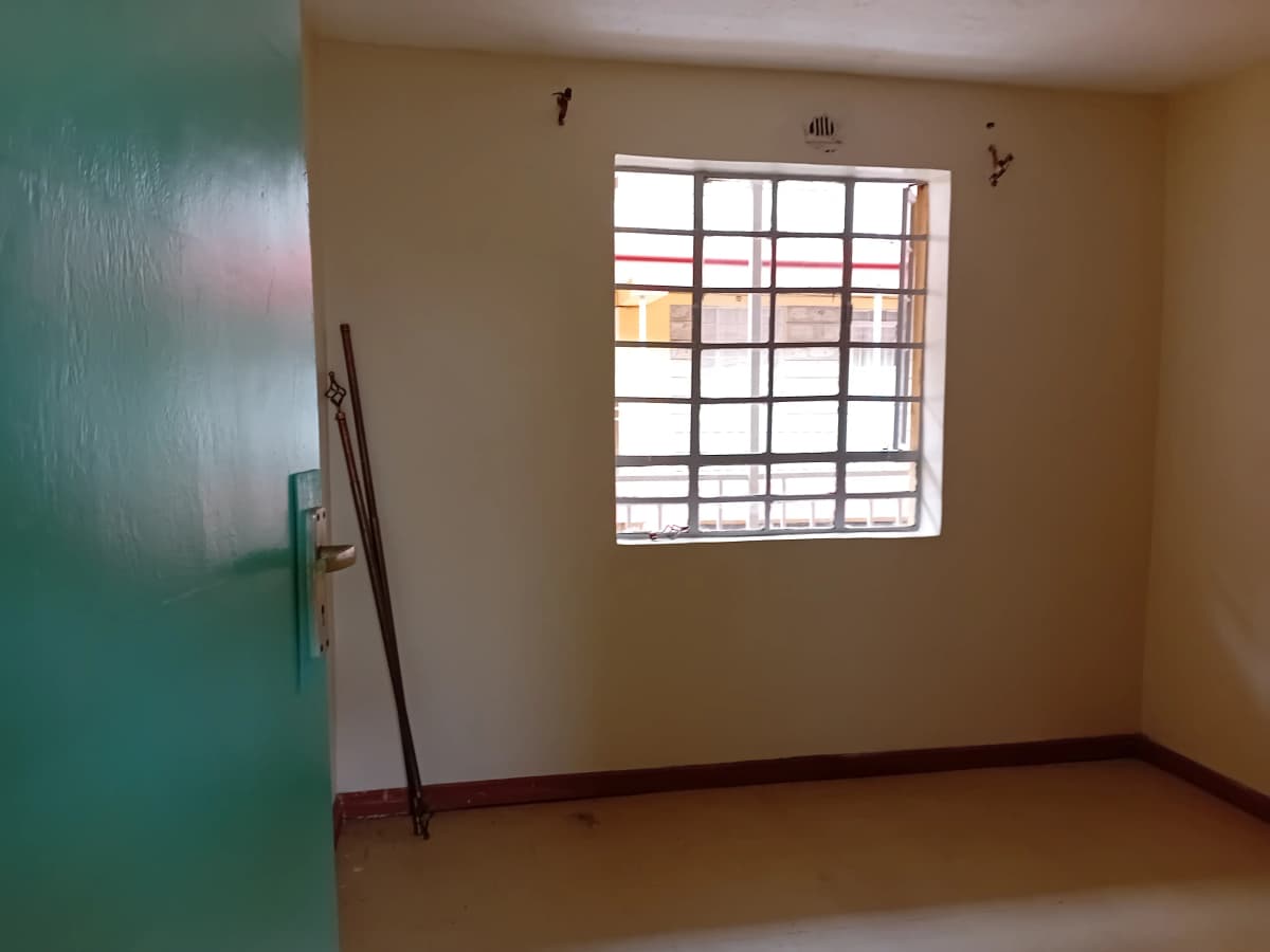 Empty bedroom with barred window and minimal furnishings