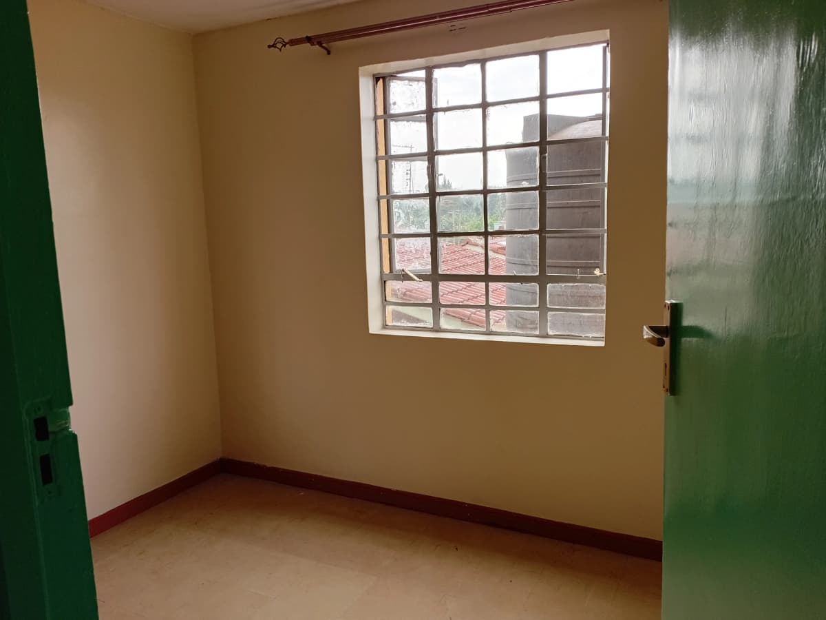Unfurnished bedroom with large window and green accent wall