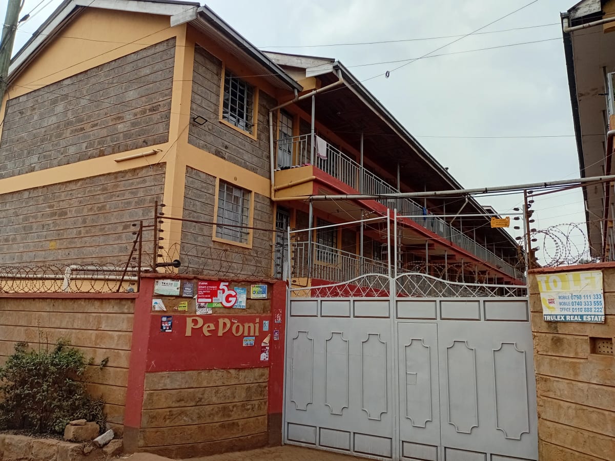Multi-story residential building with gated entrance and red signage