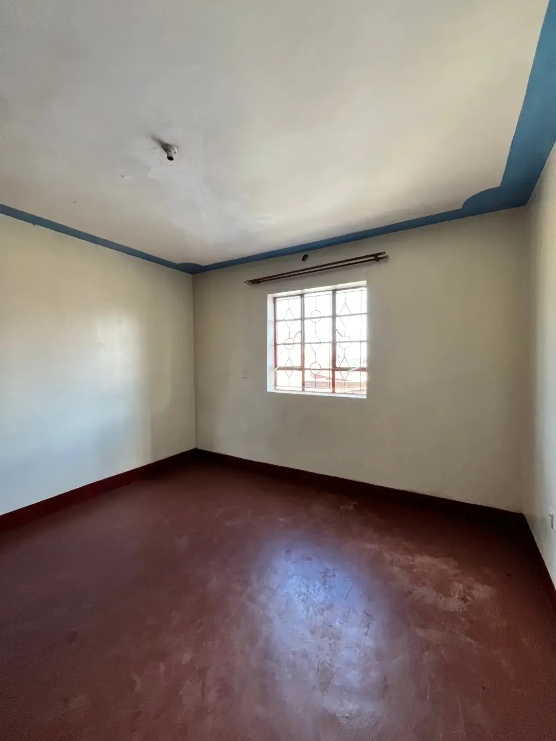 Empty bedroom with red oxide flooring and natural light