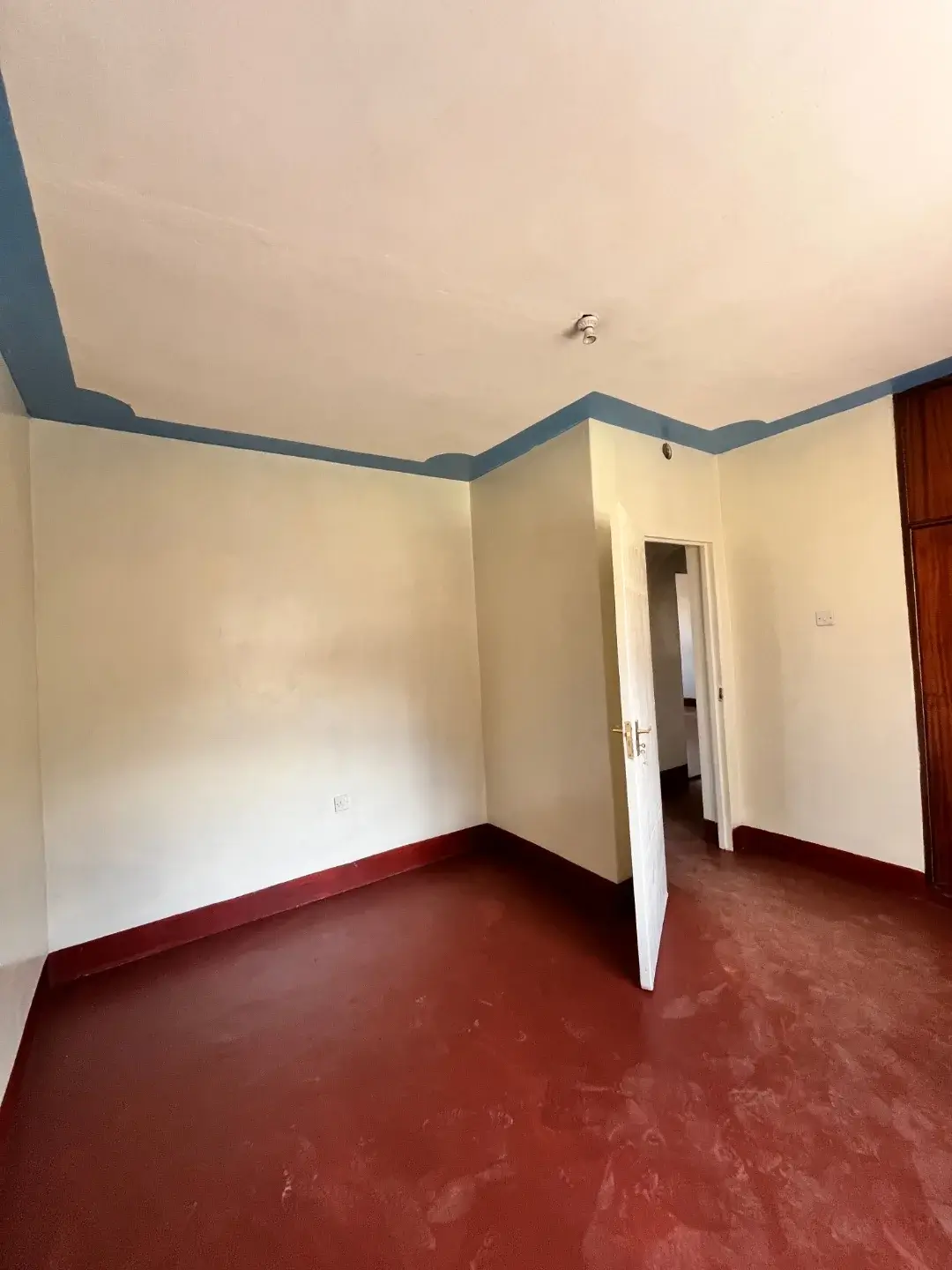 Empty bedroom with red tile floor and blue ceiling trim
