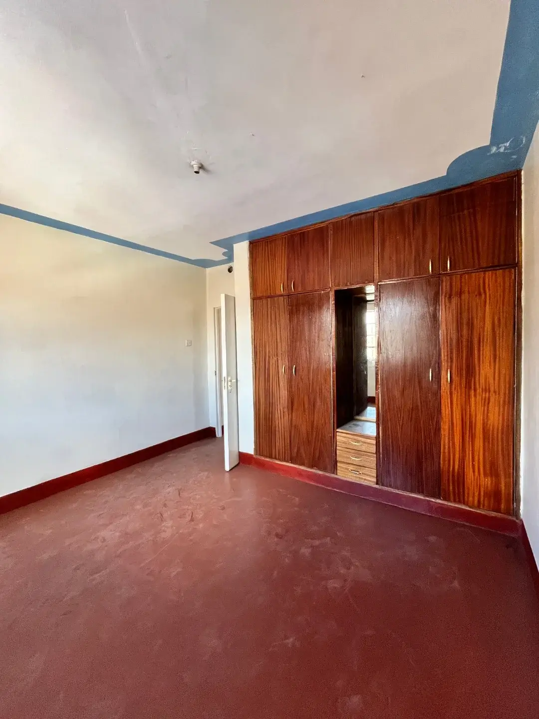 Spacious bedroom with wooden wardrobe and red floor