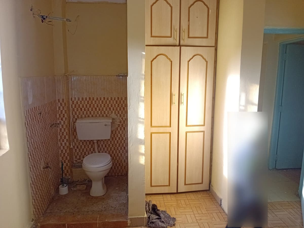 Bathroom with toilet, patterned tile walls, and glass shower enclosure