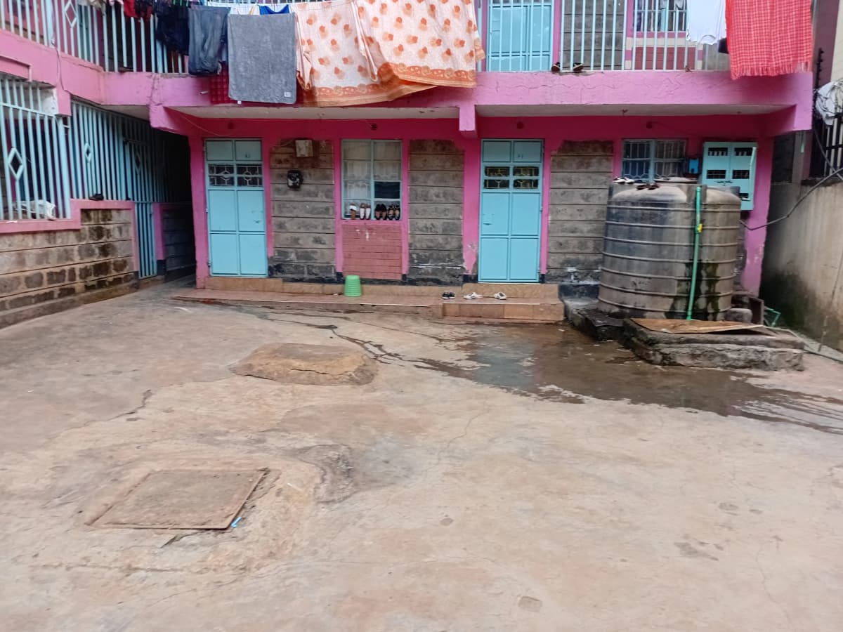 Compound entrance with pink building facade and concrete courtyard