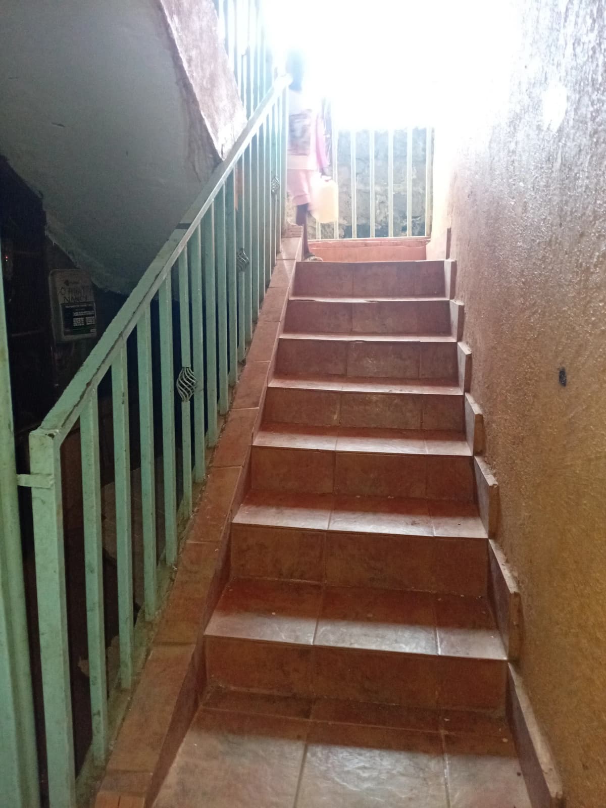 Interior staircase with green metal railing leading upward