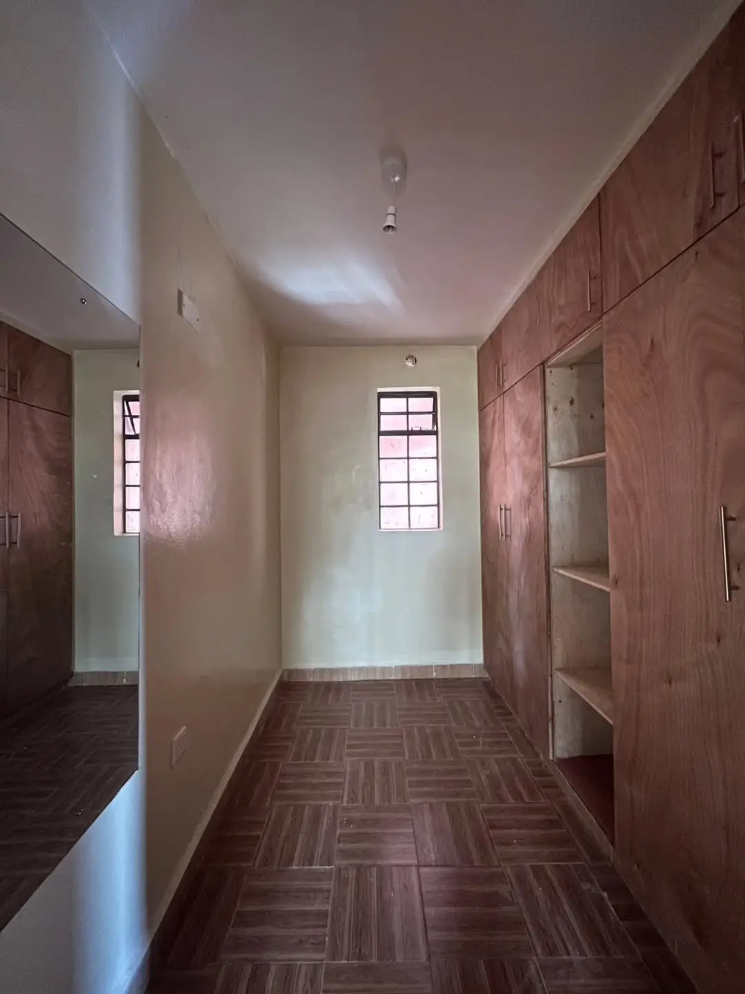 Spacious bedroom with wooden built-in wardrobes and window