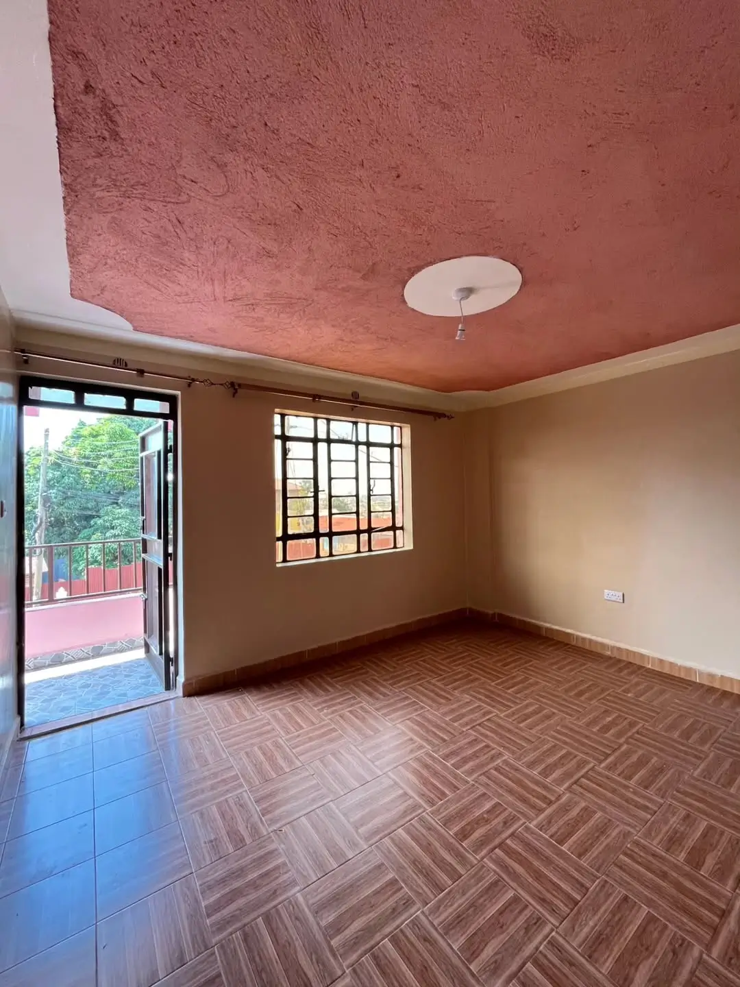 Empty bedroom with herringbone flooring and balcony access