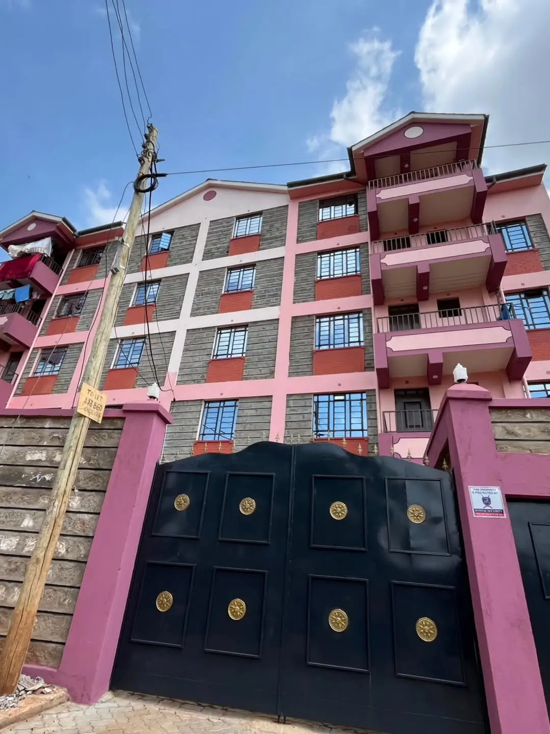 Pink and grey residential apartment building with black gate entrance