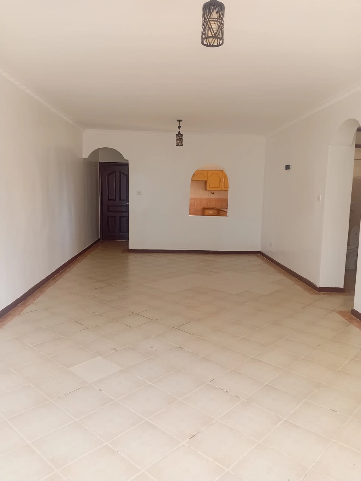 Spacious empty living room with tiled flooring and neutral walls