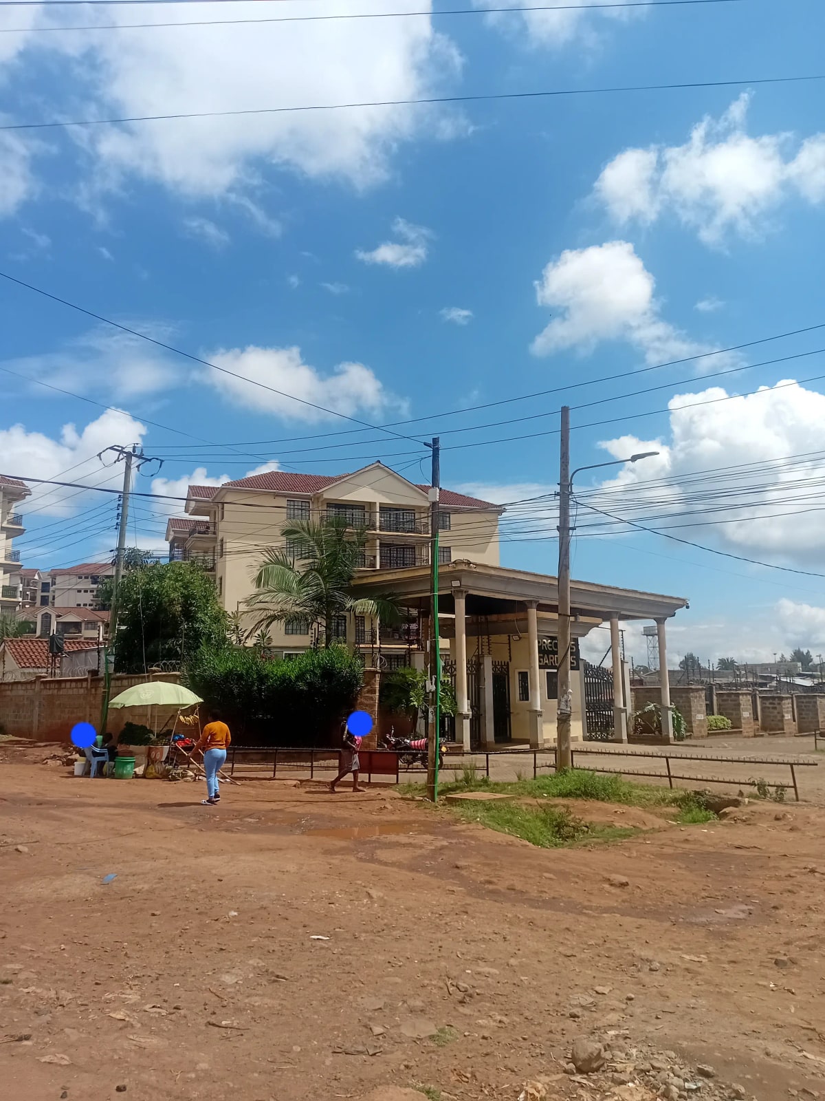 Two-story residential building with red soil compound and gate