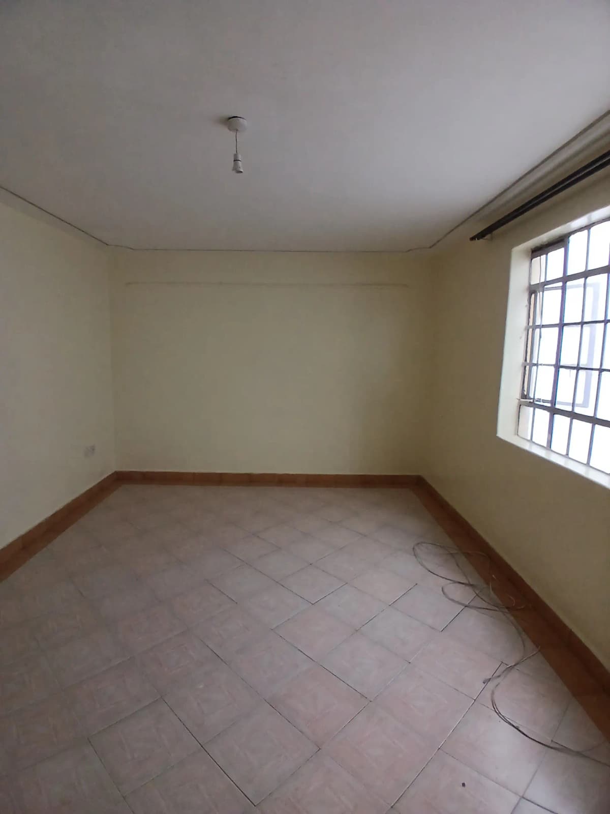 Empty bedroom with terracotta tiles and natural window light