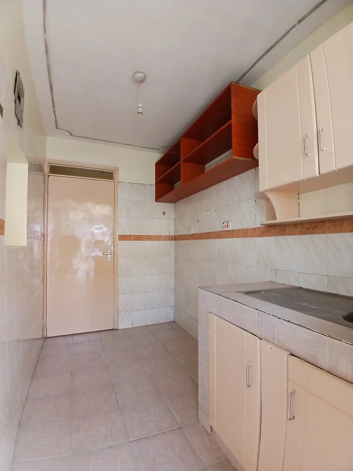 Compact kitchen with white cabinetry and red storage shelving
